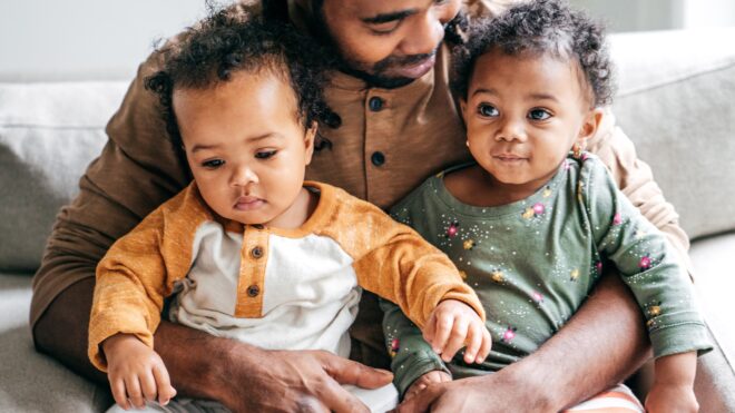 Black father holding his twin children