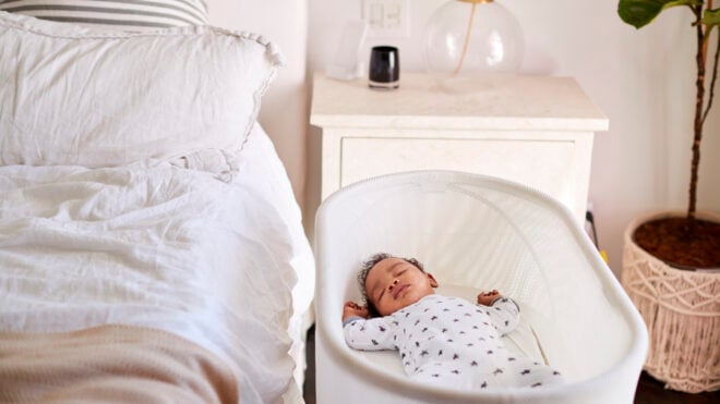 Three month old baby asleep in his cot beside the bed in his motherâ"u20acs bedroom