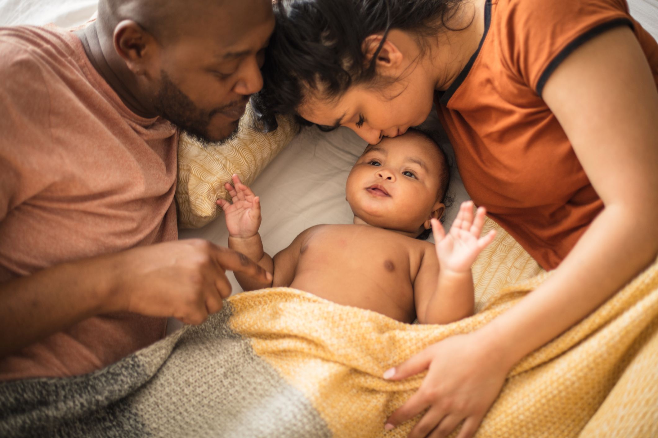 Weekend's family life. African American parents with daughter on bed.