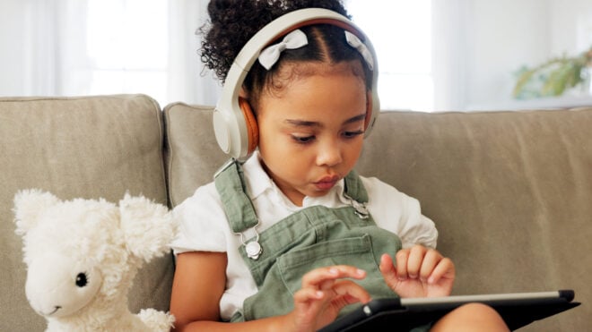 screen time, Tablet game, headphones and relax child gaming, having fun or play online games on mobile device or digital tech app. Kid entertainment, youth lifestyle and young gamer girl playing on ui touchscreen