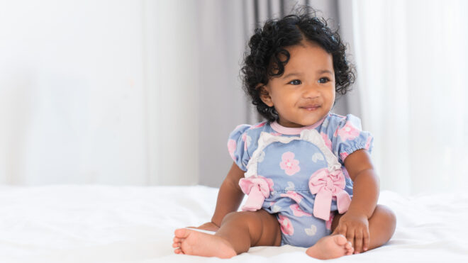 Baby girl sitting on a bed
