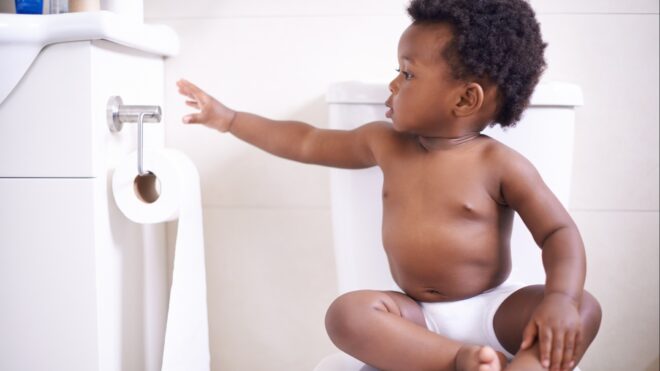A baby sitting on the toilet