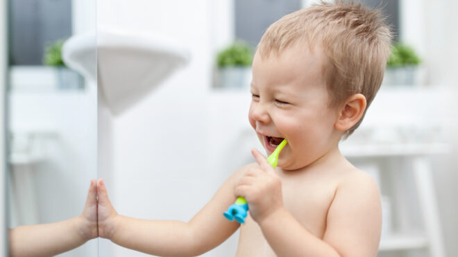 Happy toddler boy brushing his teeth