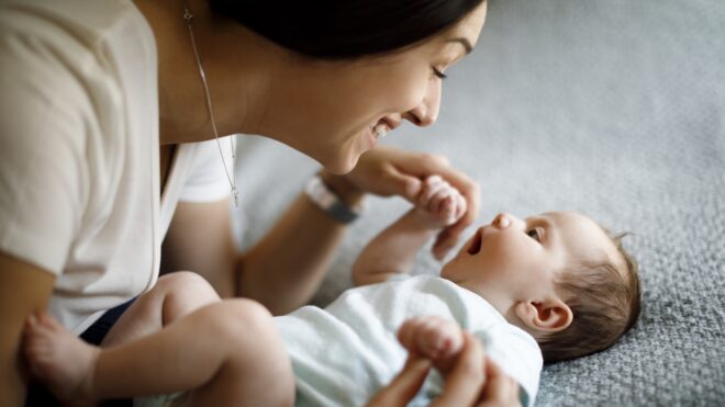 Mom talking to baby on bed